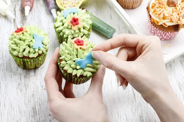 Woman decorates easter cupcakes — Stock Photo, Image