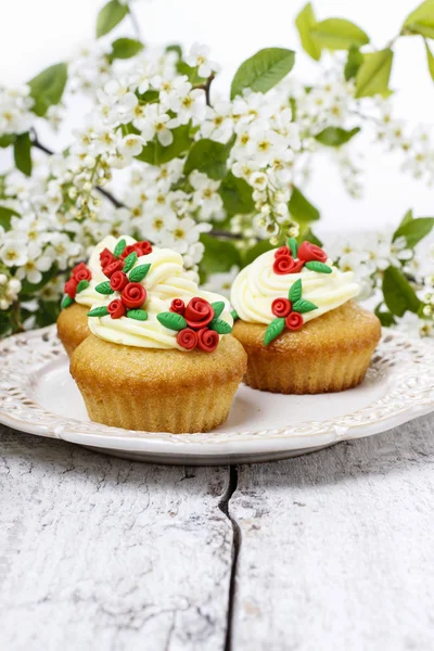 Beautiful rose cupcake and bird cherries in the background — Stock Photo, Image