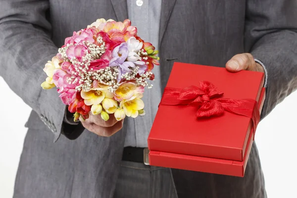 Мужчина держит красочный букет цветов фрезии и красную коробку — стоковое фото