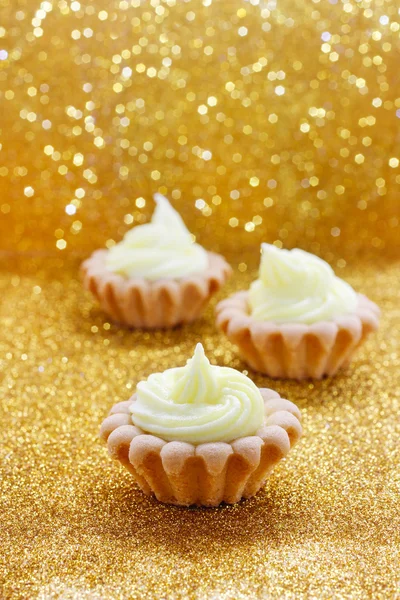 Tiny cupcakes on golden background — Stock Photo, Image