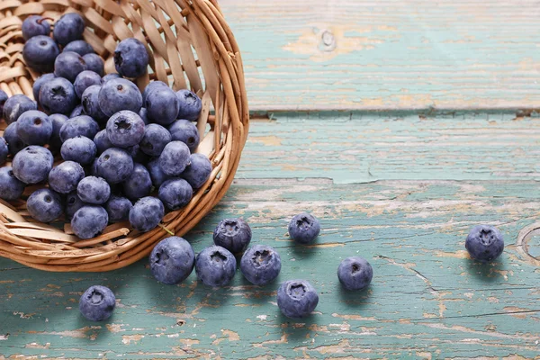 Korb mit Blaubeeren auf einem türkisfarbenen Holztisch — Stockfoto