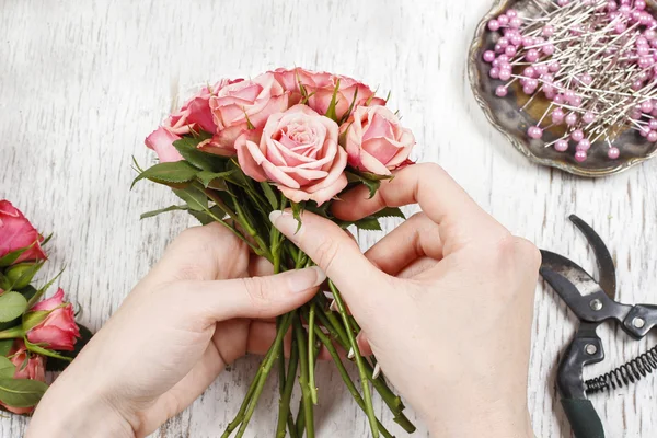 Florist bei der Arbeit. Frau macht Strauß aus rosa Rosen — Stockfoto