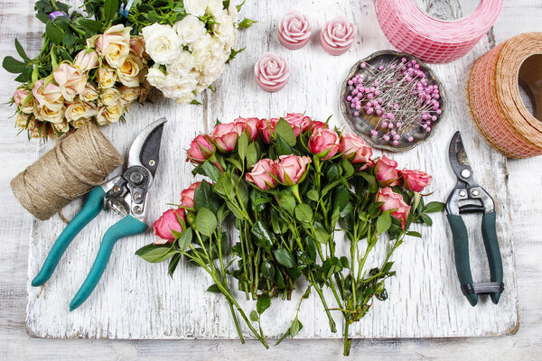 Florist at work. Woman making bouquet of pink roses