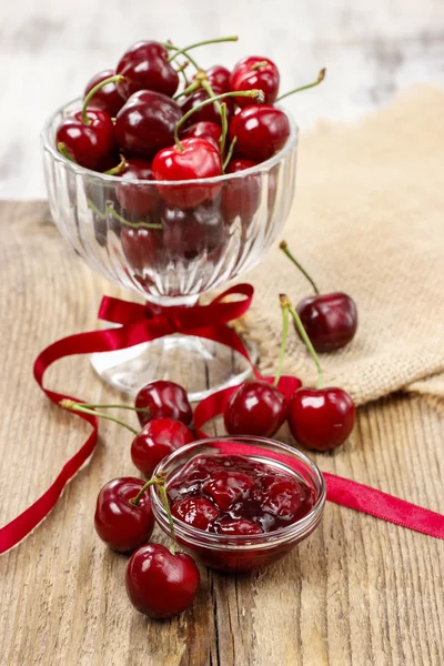 Bowl of cherry jam on wooden table and fresh cherries around — Stock Photo, Image