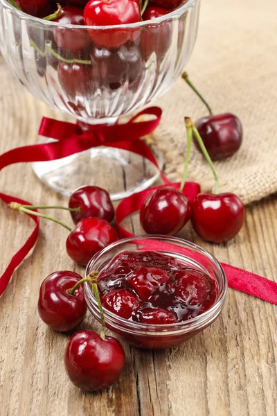 Bowl of cherry jam on wooden table and fresh cherries around — Stock Photo, Image
