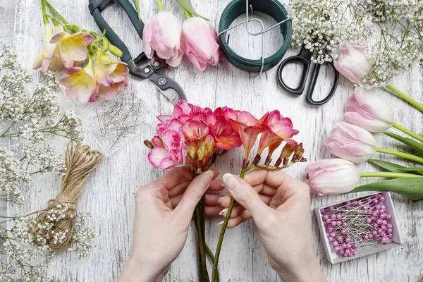 Florista no trabalho. Mulher fazendo buquê de flores freesia primavera Fotografias De Stock Royalty-Free