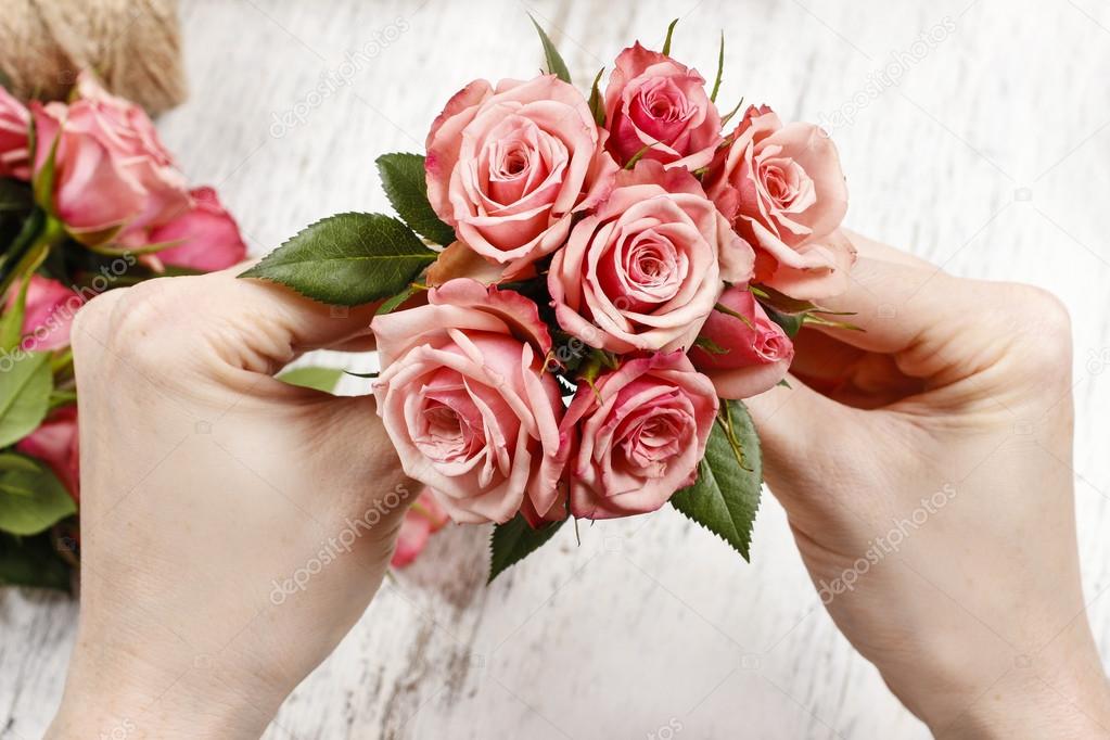 Florist at work. Woman making bouquet of pink roses