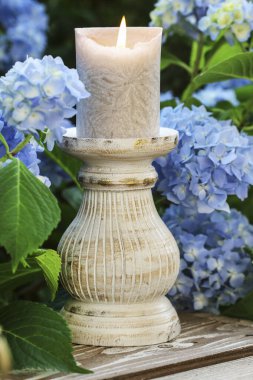 A candle among beautiful blue hortensia flowers in the garden. Party decor