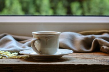 Tahta bir masanın üzerinde porselen bir fincan çay. Dinlenme zamanı.