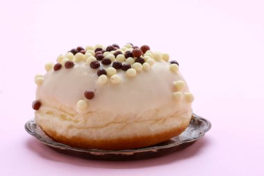 Pembe arka planda beyaz çikolatalı bir çörek. Parti tatlısı