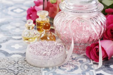 Lavantalı deniz tuzu ile kase. Etrafındaki güller ve diğer kozmetikler. Spa zamanı