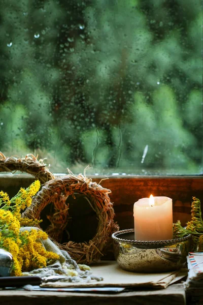 A candle by the window and autumn plants around it. Home decor