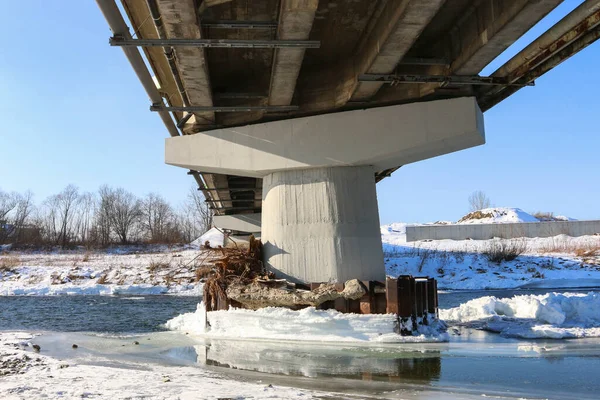 Bridge pillars covered with ice, frozen river. Winter time