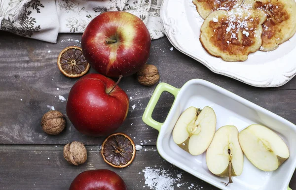 Raw apples and plate with apple fritters on rustic wooden table. Healthy food