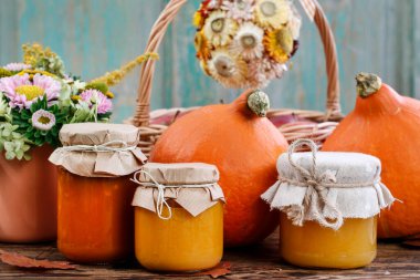 Balkabağı reçelli cam kavanozlar ve bal. Masada taze sebzeler var. Sonbahar dekoru