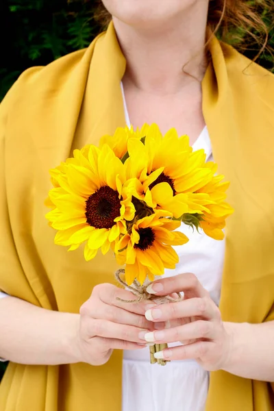 The woman is holding a bouquet of sunflowers. Summer party deecor