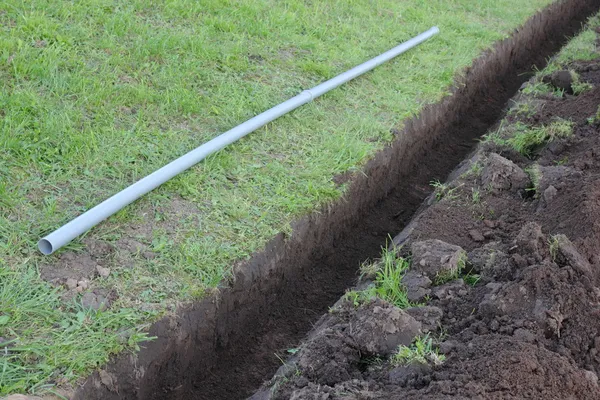 Trench in the ground and gray plastic pipe — Stock Photo, Image