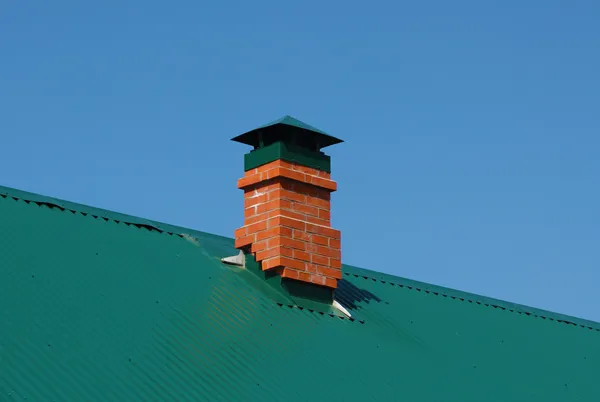 Komin murowany w zielone dachy metalowe — Zdjęcie stockowe