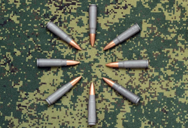 Acht cartridges op camouflage achtergrond opsommingstekens georiënteerde binnen — Stockfoto