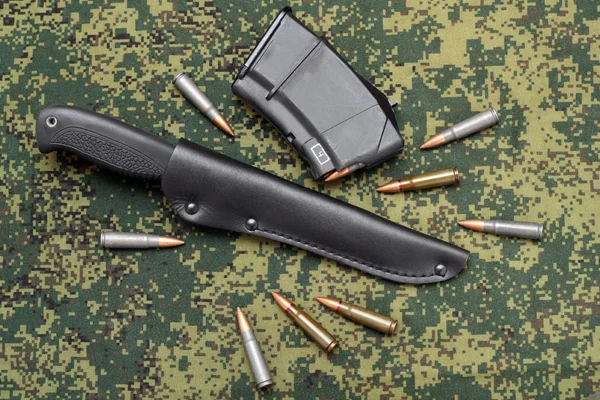 Vojenský nůž v černé kožené pochvy, časopis a kazet na maskování pozadí — Stock fotografie