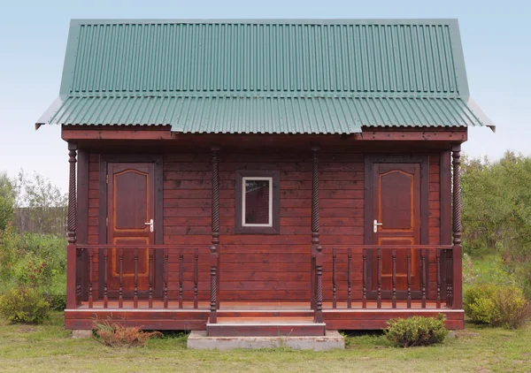 Klein houten huis onder groen metalen dak — Stockfoto