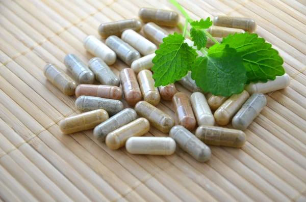 Herbal capsules with mint leaves — Stock Photo, Image