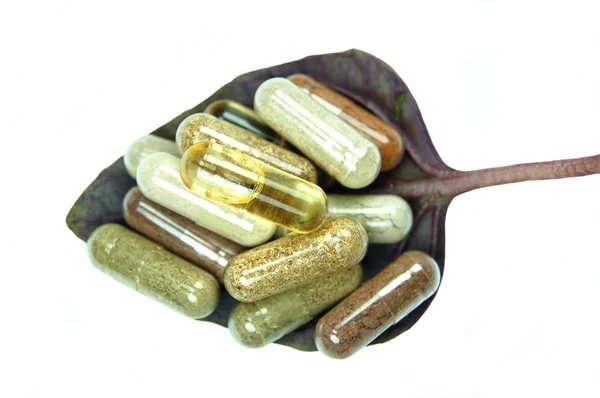 Herbal capsules in basil leaf — Stock Photo, Image