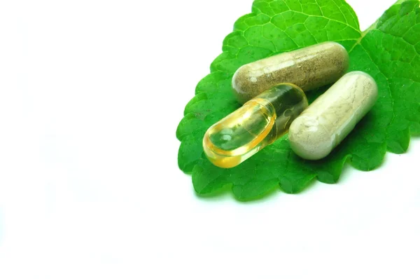 Herbal capsules on melissa leaf — Stock Photo, Image