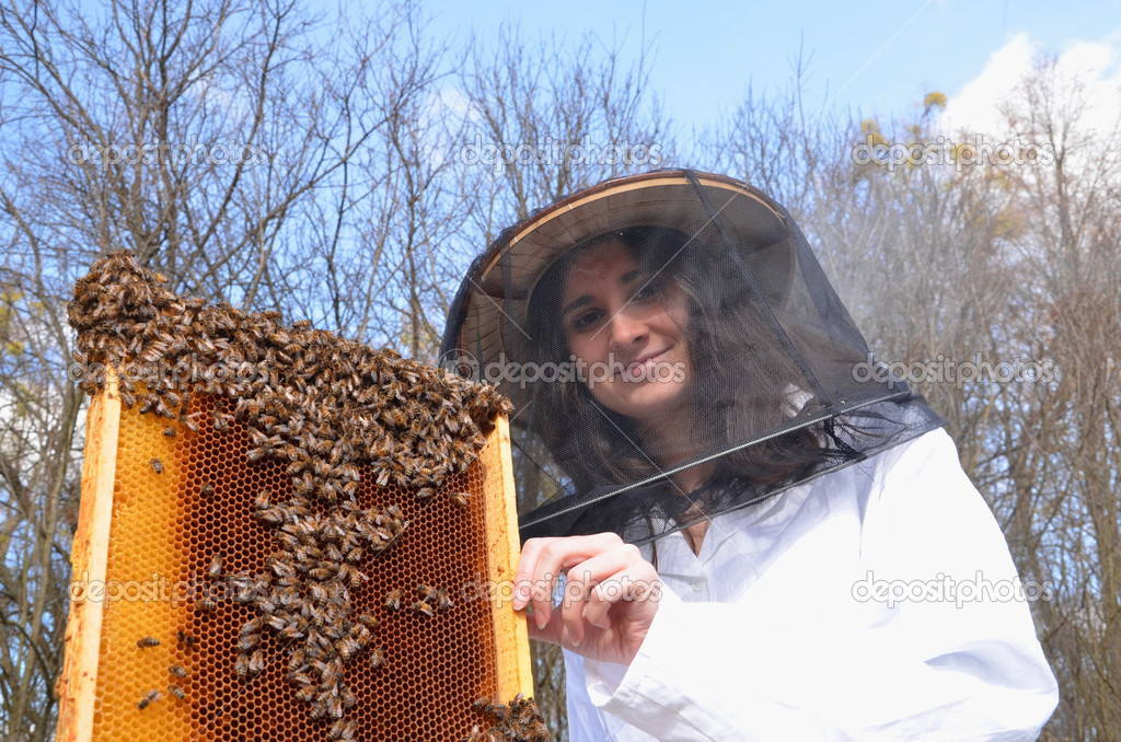 Young girl beekeeper working in apiary