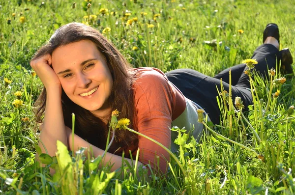Menina morena atraente bonita está deitada em um prado — Fotografia de Stock