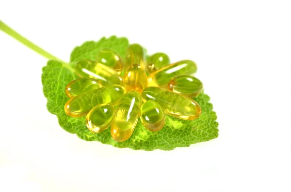 Fish oil capsules on sage leaf — Stock Photo, Image