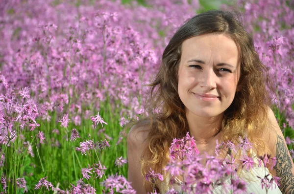 Piękny atrakcyjny dziewczynka na wspaniały łąka pełna kwiatów dzikiego — Zdjęcie stockowe