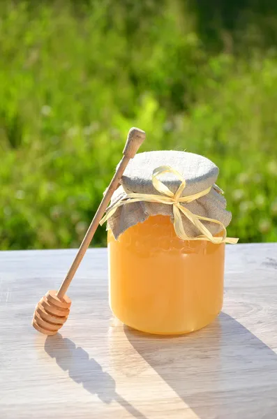 Wooden dipper and jar full of delicious fresh honey in apiary — Stock Photo, Image