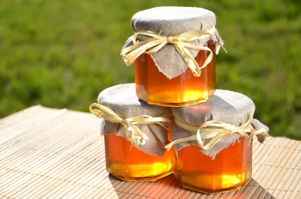 Três jarros cheios de mel fresco delicioso — Fotografia de Stock