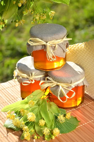Potten van vers en lekker honing met linden bloemen en honingraat — Stockfoto