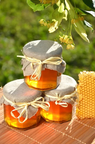 Vasi di miele fresco e delizioso con fiori di tiglio e favo — Foto Stock