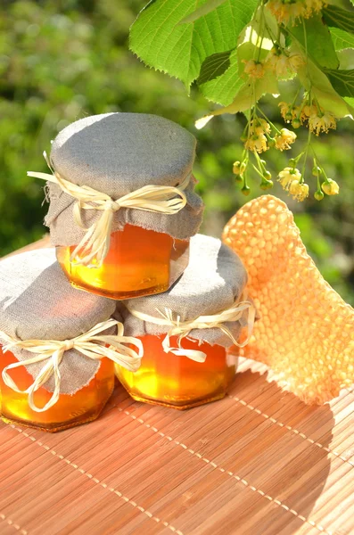 Potten van vers en lekker honing met linden bloemen en honingraat — Stockfoto