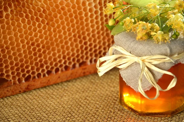 Frasco de mel fresco e delicioso com flores de tília e favo de mel — Fotografia de Stock