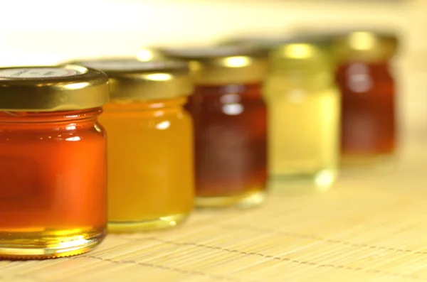 Variedade de frascos cheios de mel fresco delicioso — Fotografia de Stock