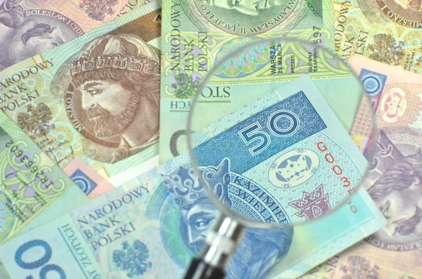 Polish zloty banknotes under magnifying glass — Stock Photo, Image