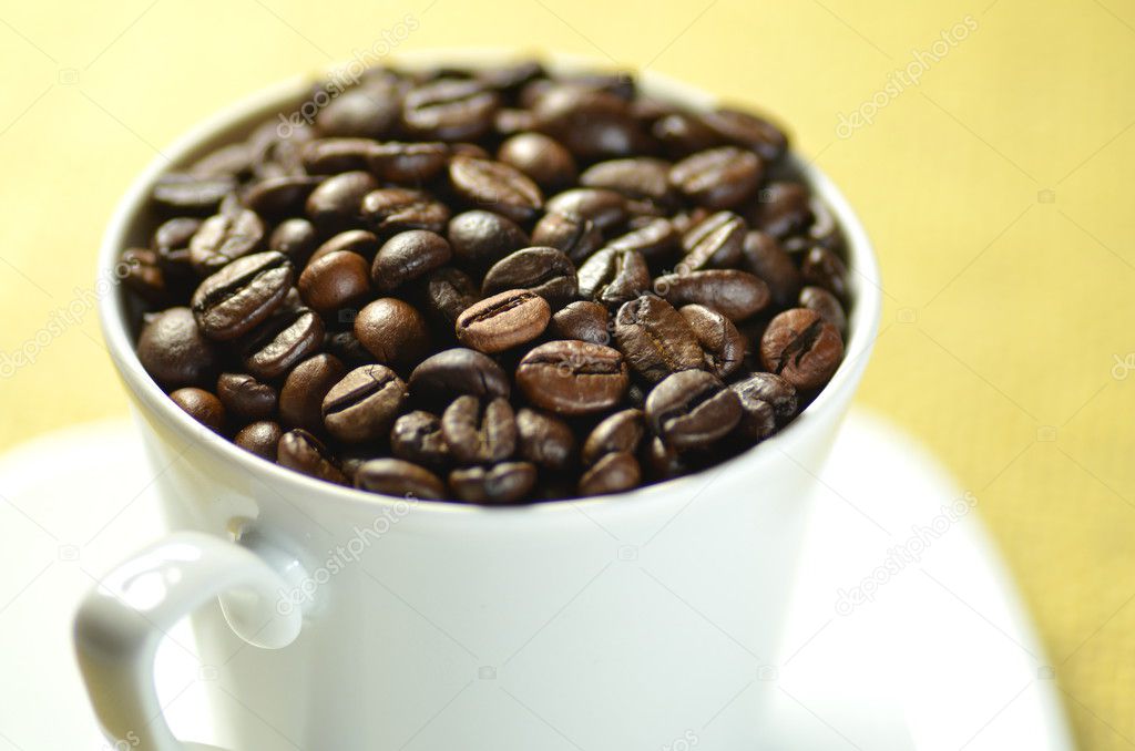 White coffee cup full of coffee beans