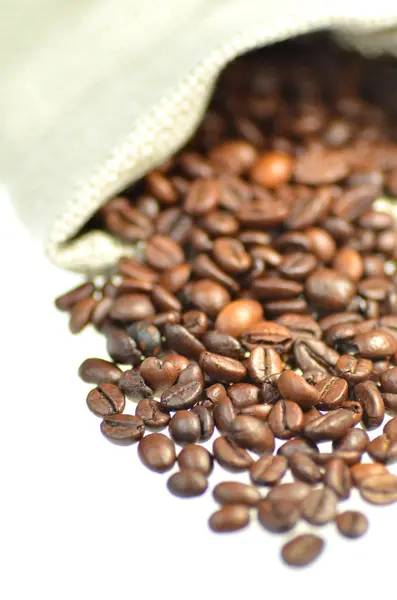 Kaffebönor utspridda ur väskan isolerad på vit — Stockfoto
