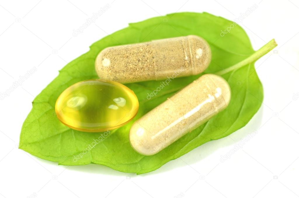 herbal capsules and fish oil capsule on mint leaf isolated on white background
