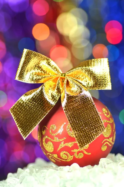 Decoración navideña, bola roja de Navidad con lazo dorado en fondo bokeh — Foto de Stock