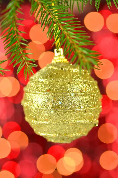 Christmas decoration, golden Christmas ball hanging on spruce twig against bokeh background — Stock Photo, Image
