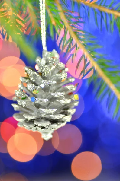 Christmas decoration, Christmas silver cone hanging on spruce twig against bokeh background — Stock Photo, Image
