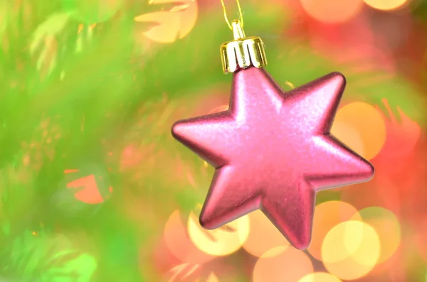 Christmas decoration, pink Christmas star ball hanging on spruce twig against bokeh background — Stock Photo, Image
