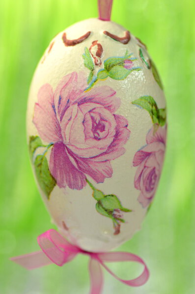 Easter egg decorated with flowers made by decoupage technique on green background