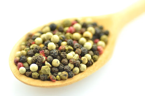 Closeup of colored pepper on a wooden spoon isolated on white background — Stock Photo, Image