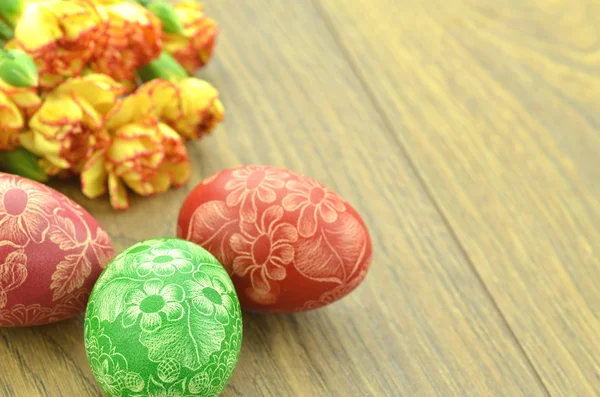 Scratched handmade Easter eggs and carnation flowers — Stock Photo, Image